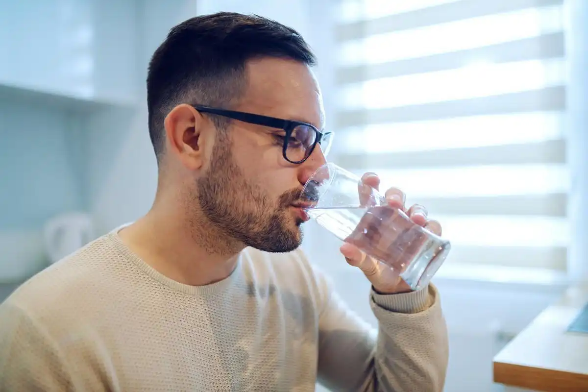 Side view of man sitting and drinking water.