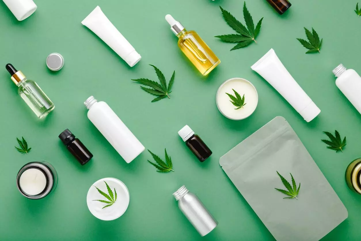 Various topicals on a green surface, with cannabis leaves scattered around.
