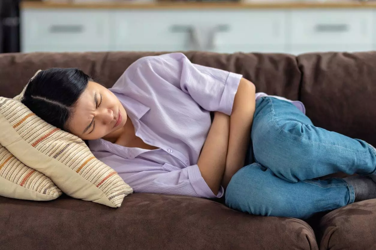 A woman experiencing intense spasms while clutching her abdomen.