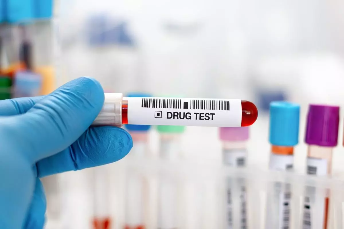 A physician holding a vial of blood for drug analysis.