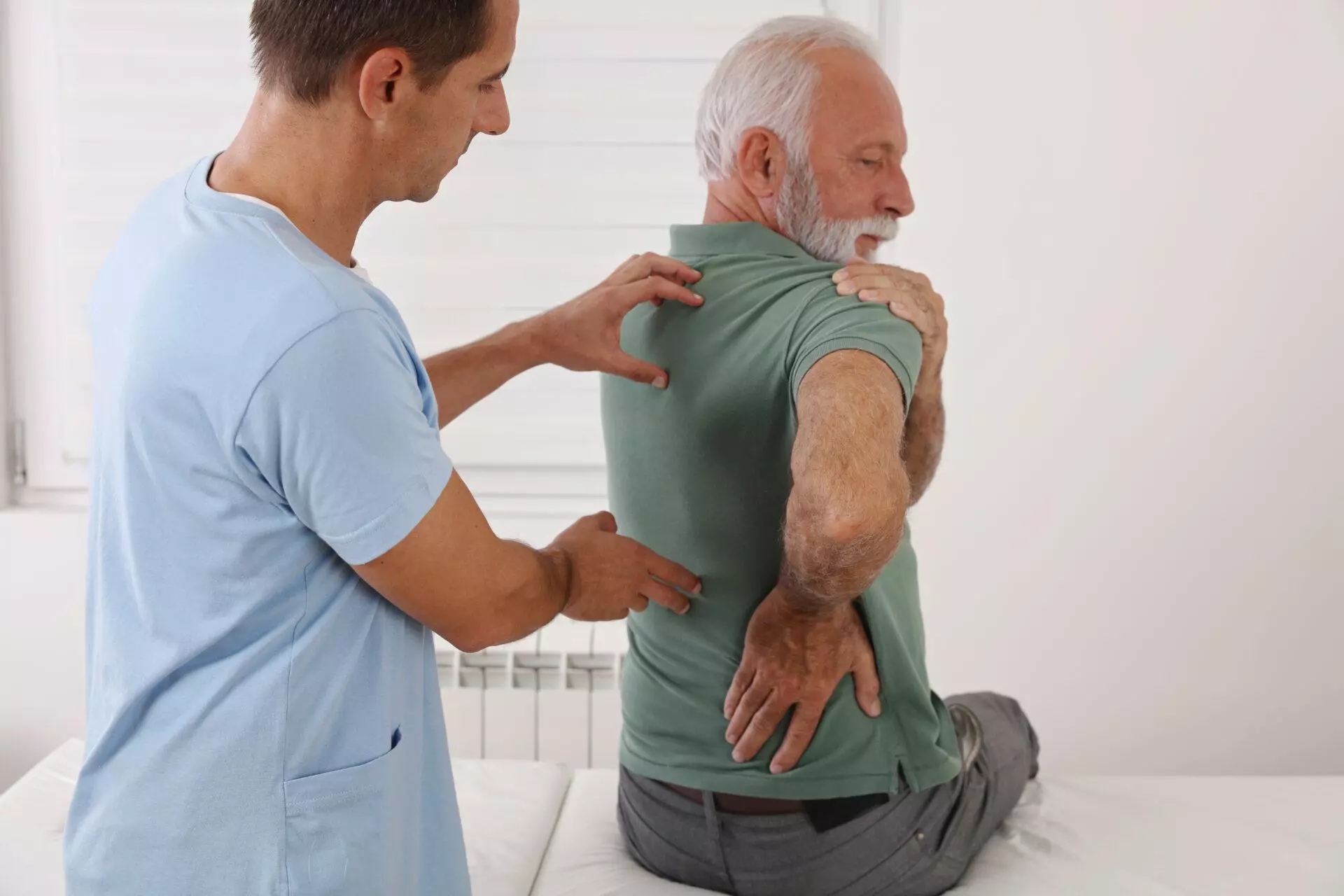 enior man with a chiropractor examining backache