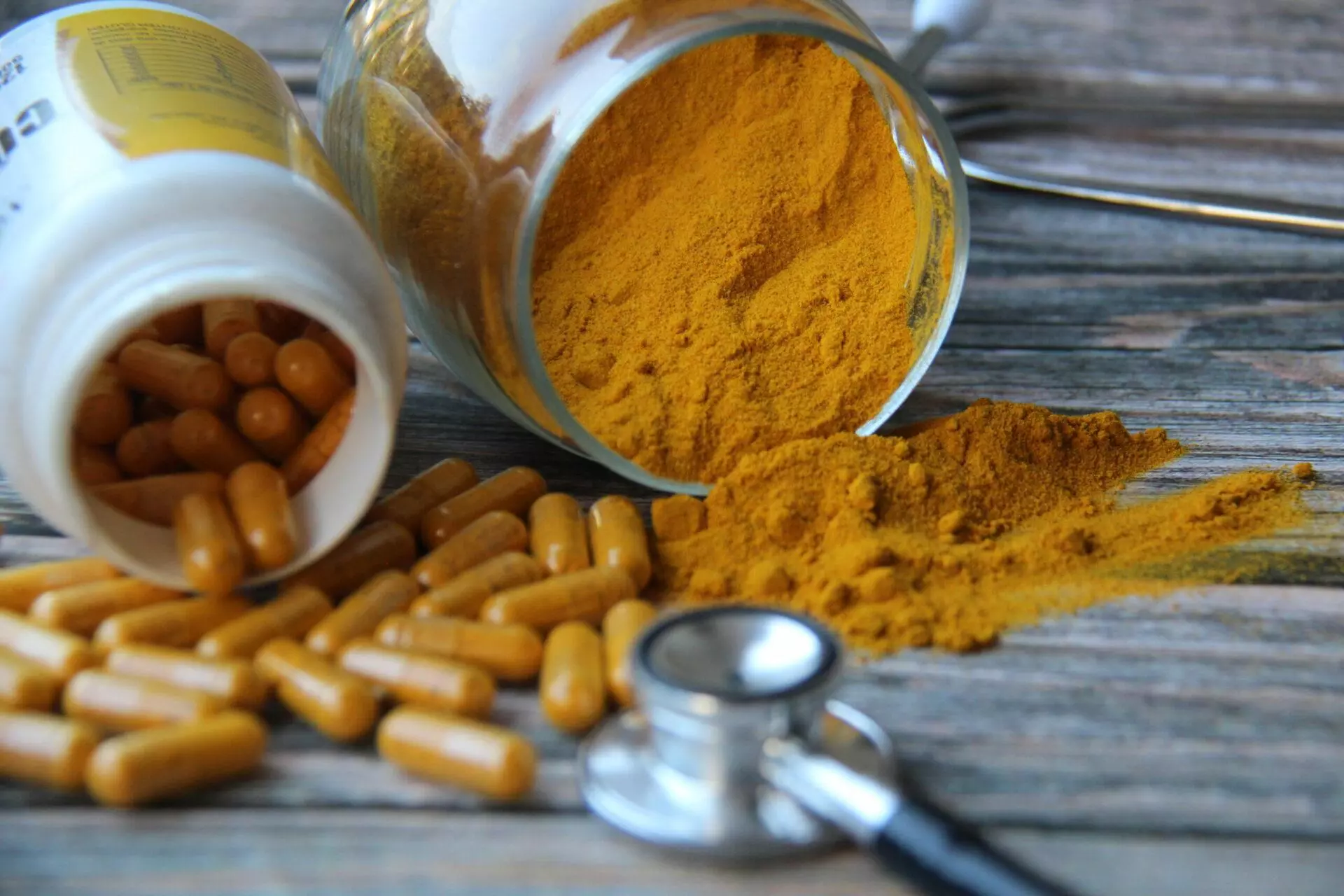 Turmeric powder and turmeric pills with a stethoscope on a wooden table