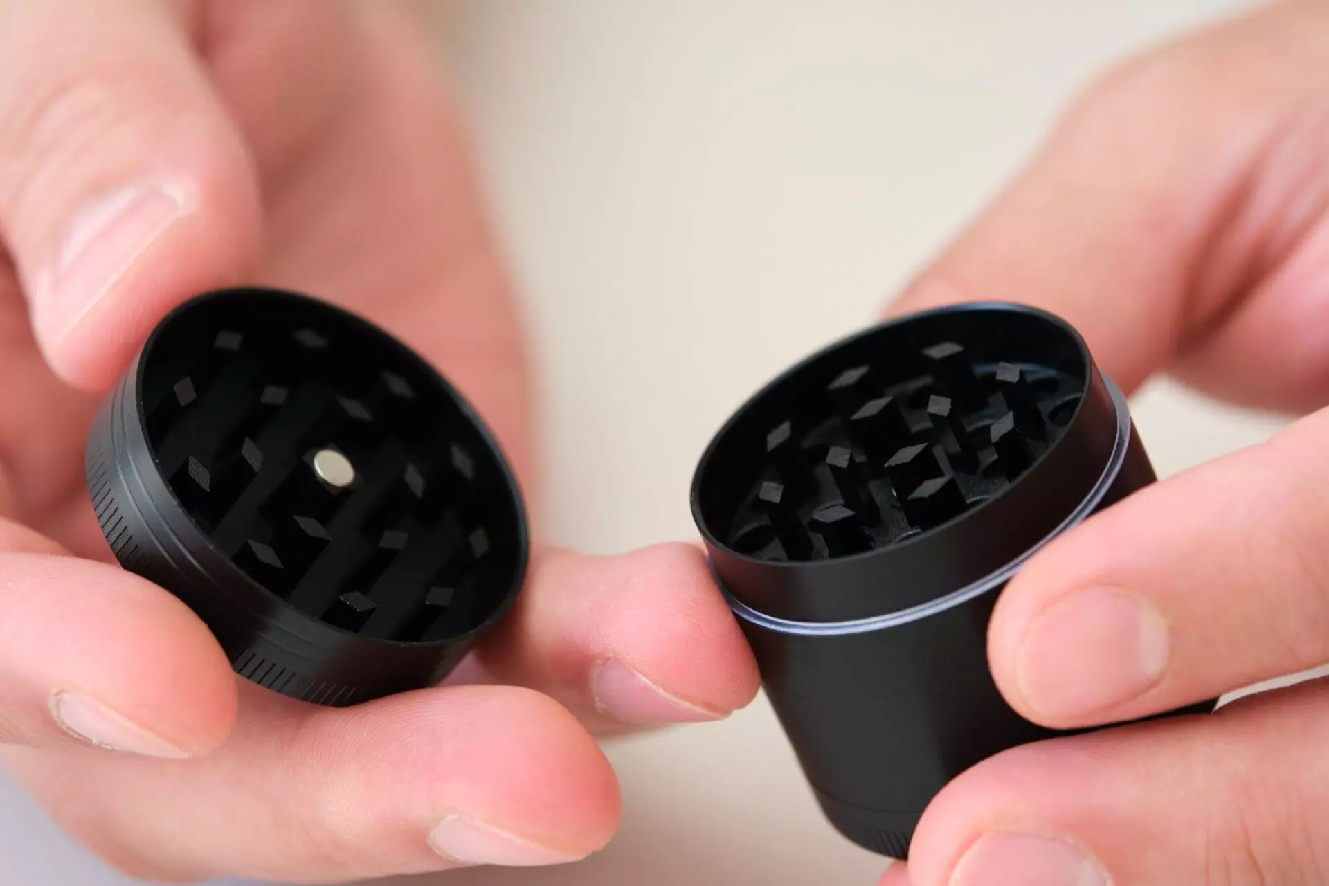 Two hands holding an empty marijuana grinder.