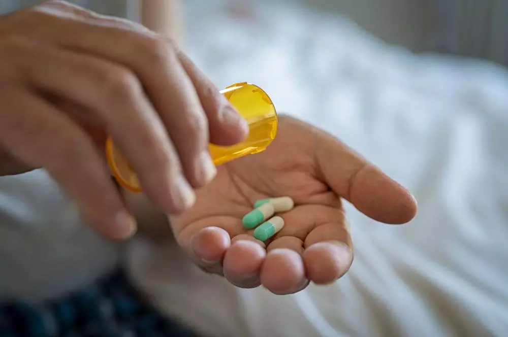 Close-up of man’s hand taking medicine from a pill bottle