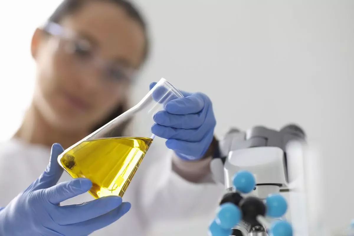 Close-up of a researcher holding a flask filled with a yellow fluid.