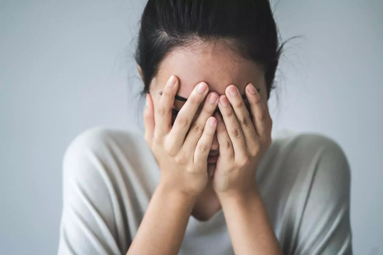 A young girl covering her face with her hands.