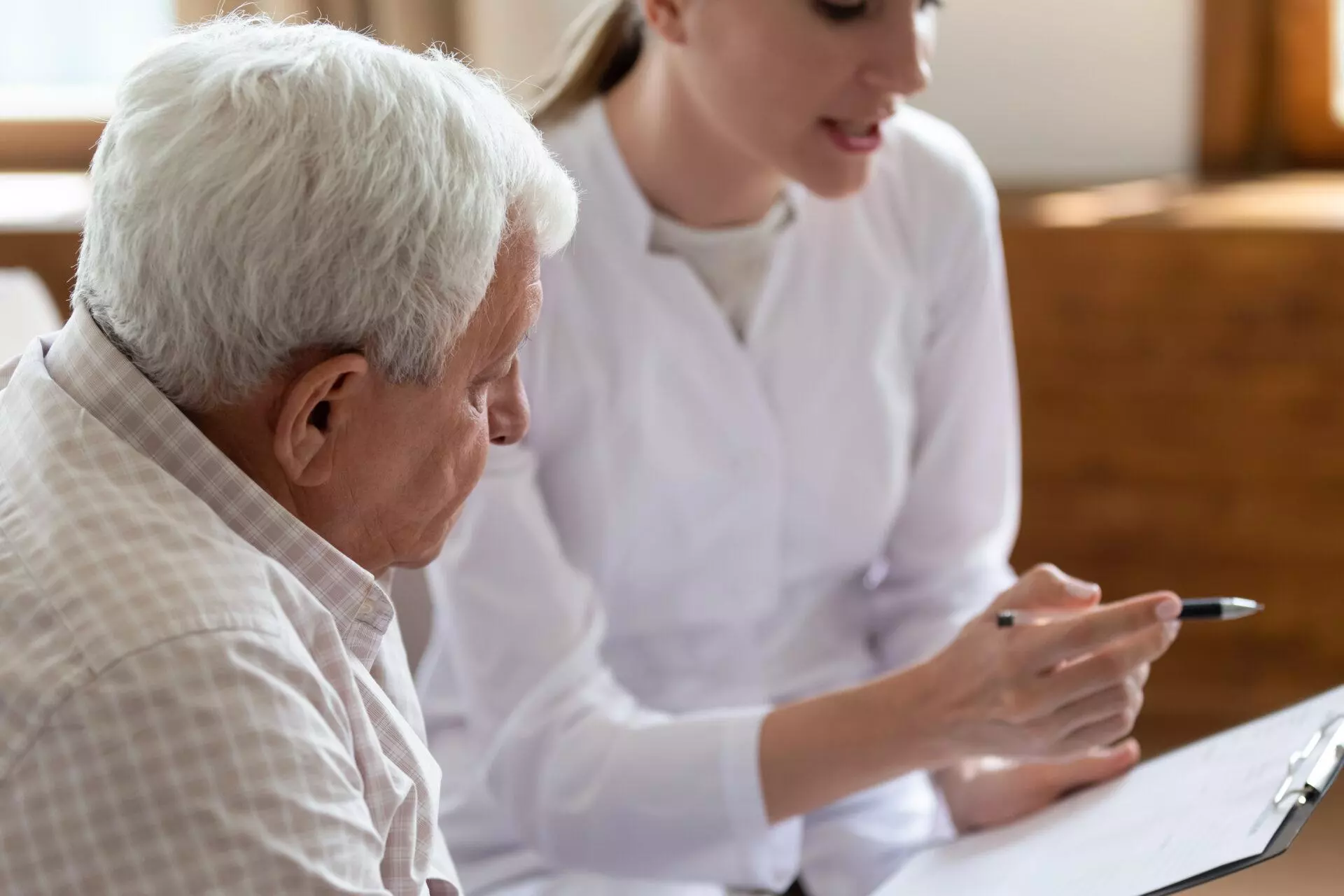 Attentive elderly male patient listening to a young female doctor.