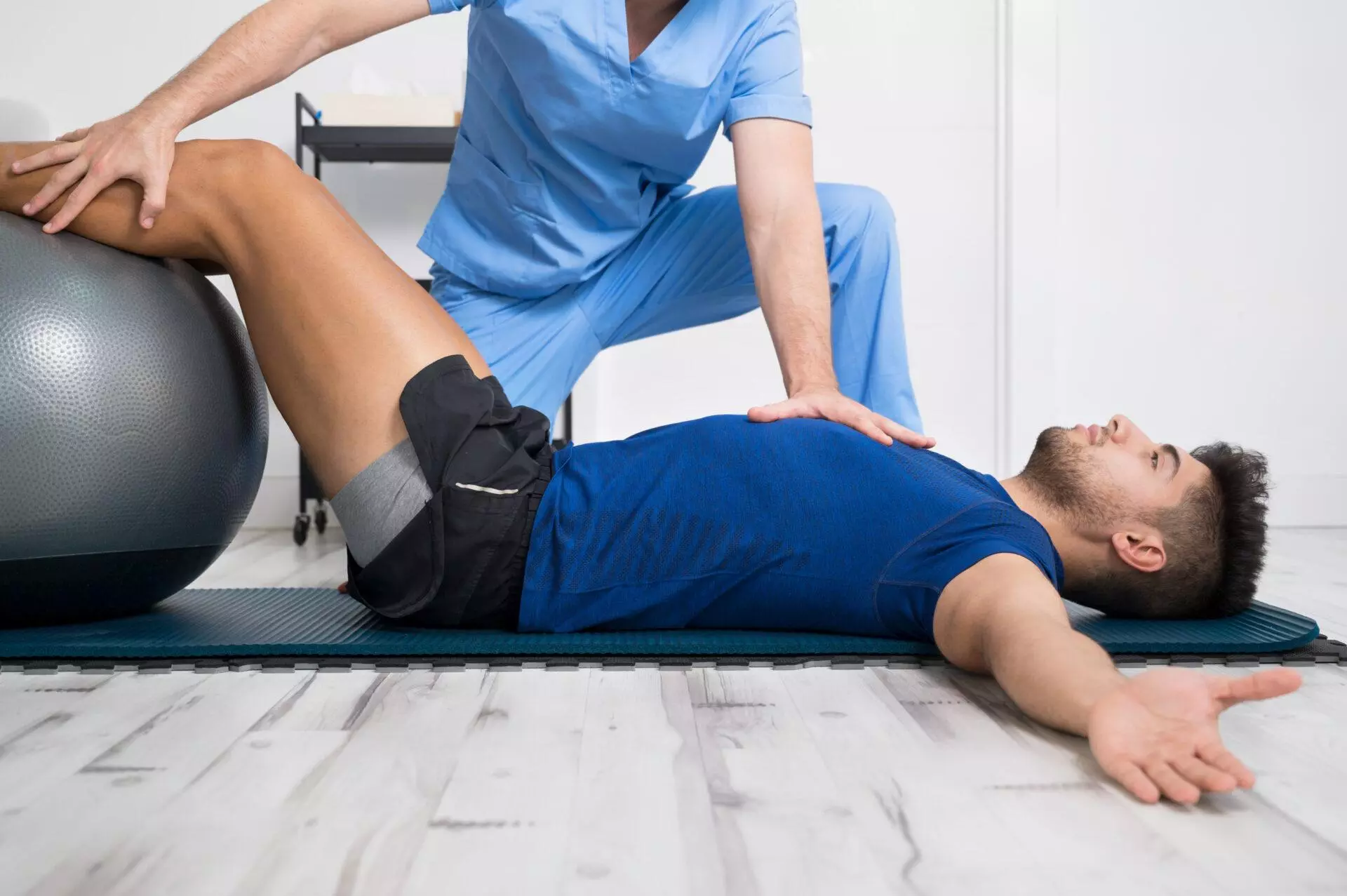 Physiotherapist helps young patient with pilates exercises.