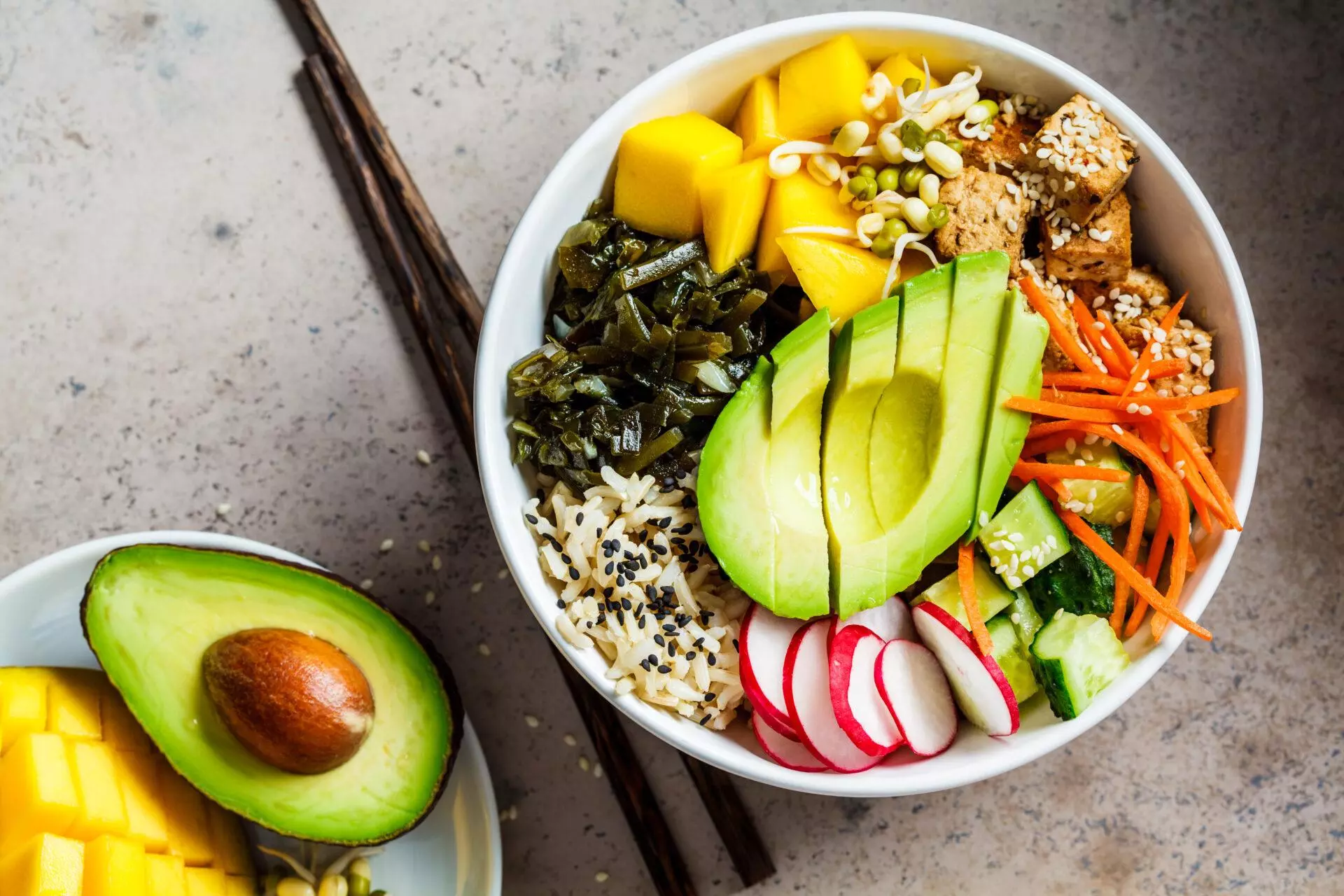 Vegan poke bowl with avocado, tofu, rice, seaweed, carrots and mango.