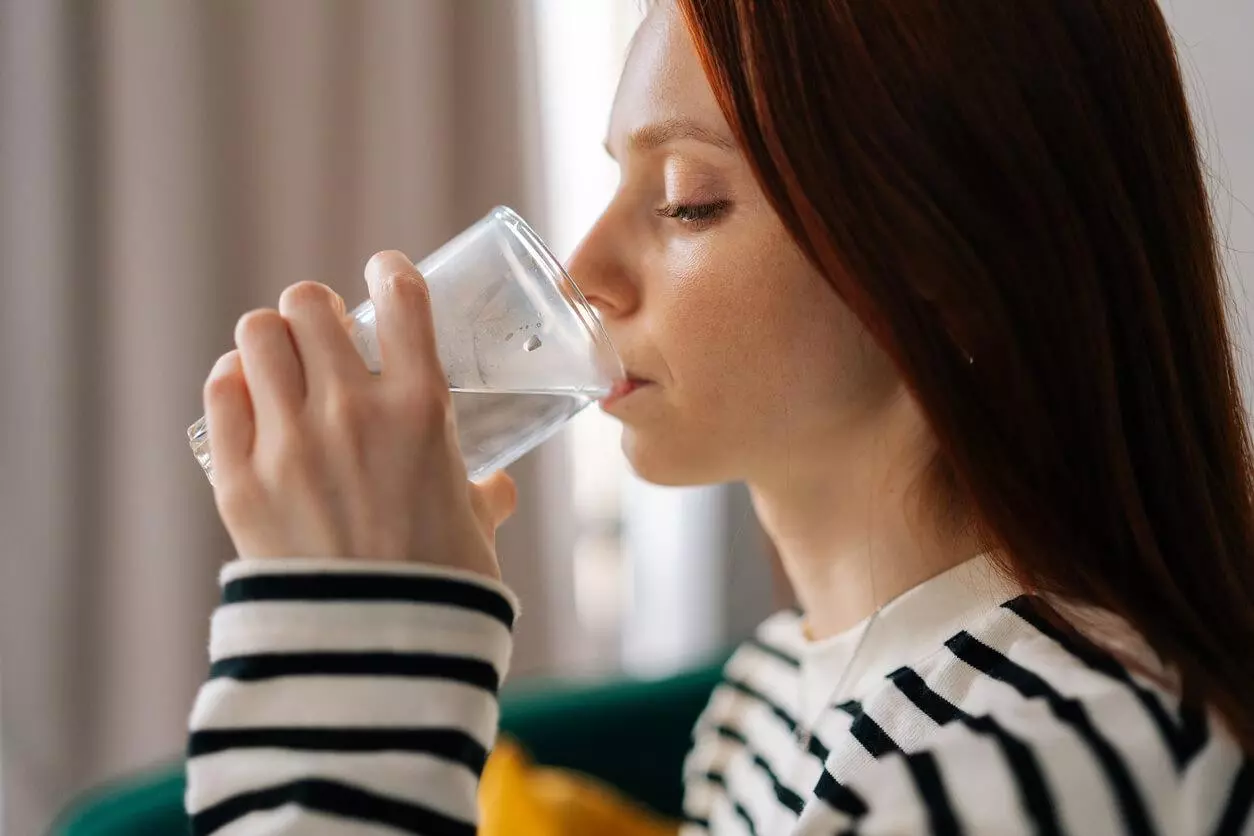 A close-up of a woman drinking still water in the comfort of her home.