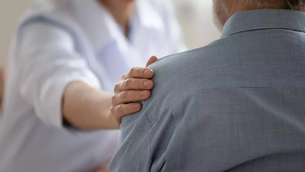 Close-up of caring doctor touching the mature patient’s shoulder