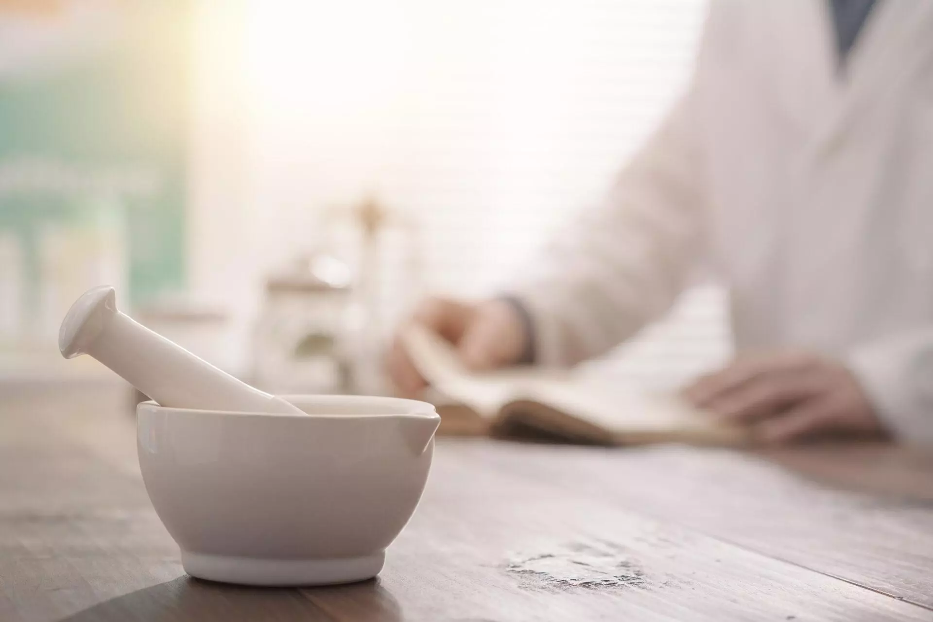 Close-up of a pestle and mortar, with a pharmacist visible in the background.