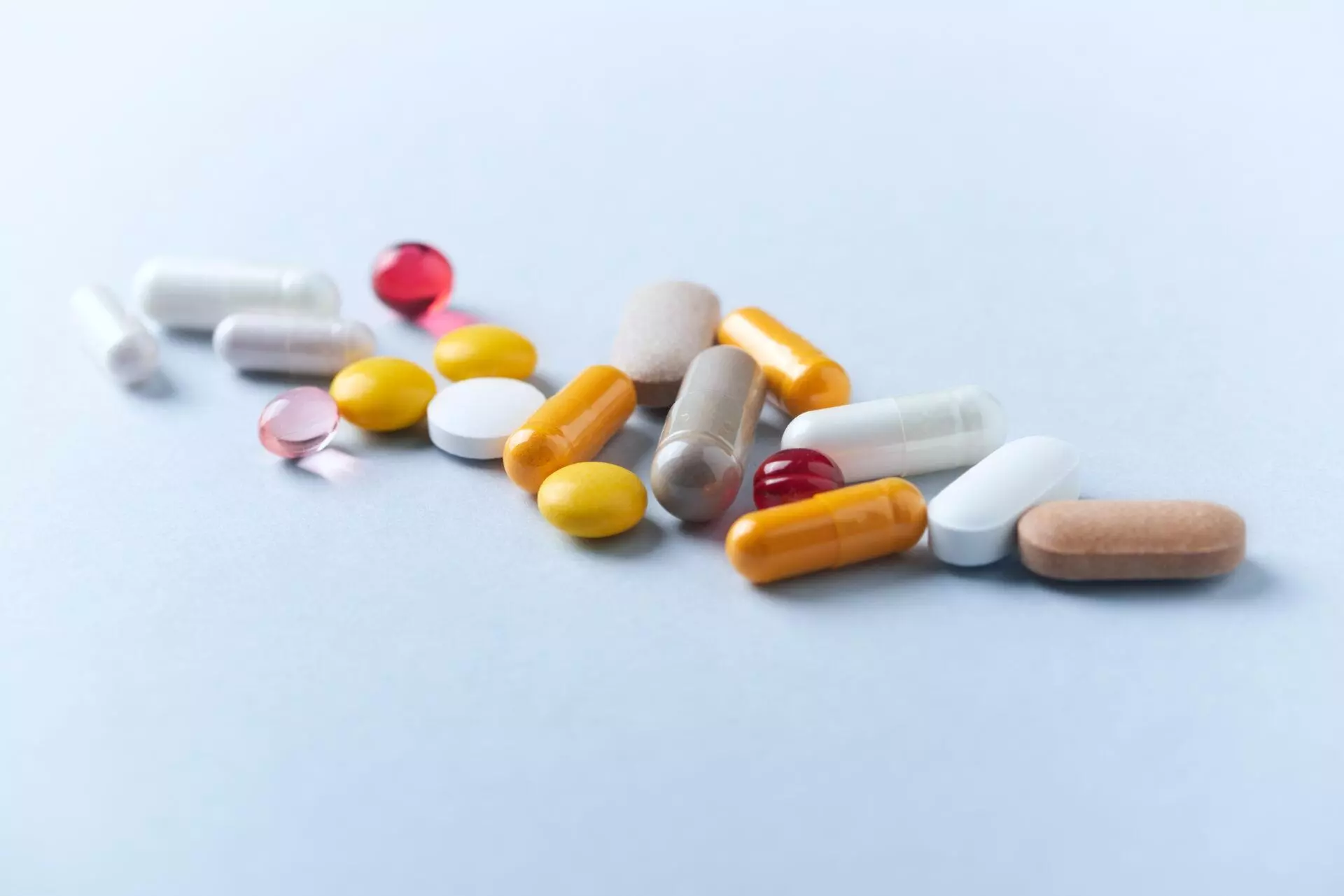 Multicolor vitamins and supplements on bright paper background.