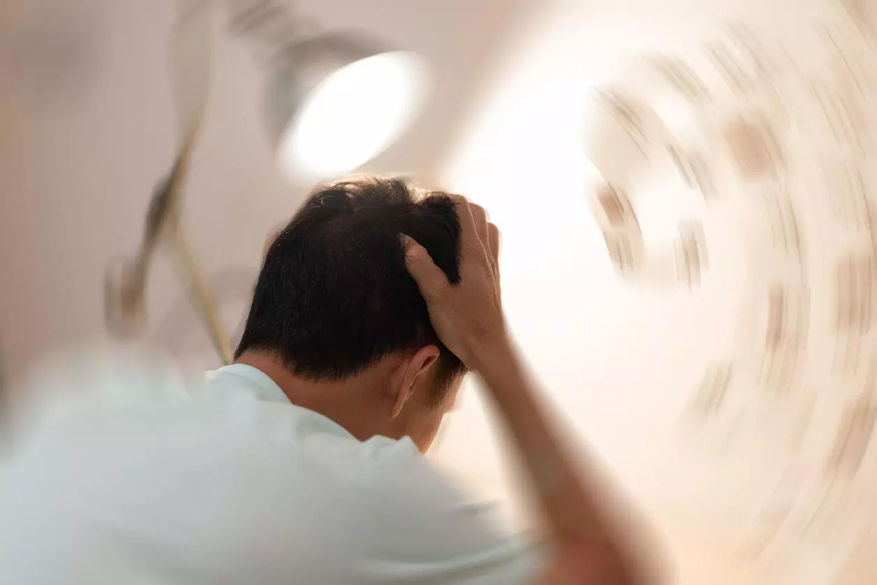 A person holding their head, experiencing dizziness or disorientation from a cannabis high, with the background appearing blurred to indicate a spinning sensation.