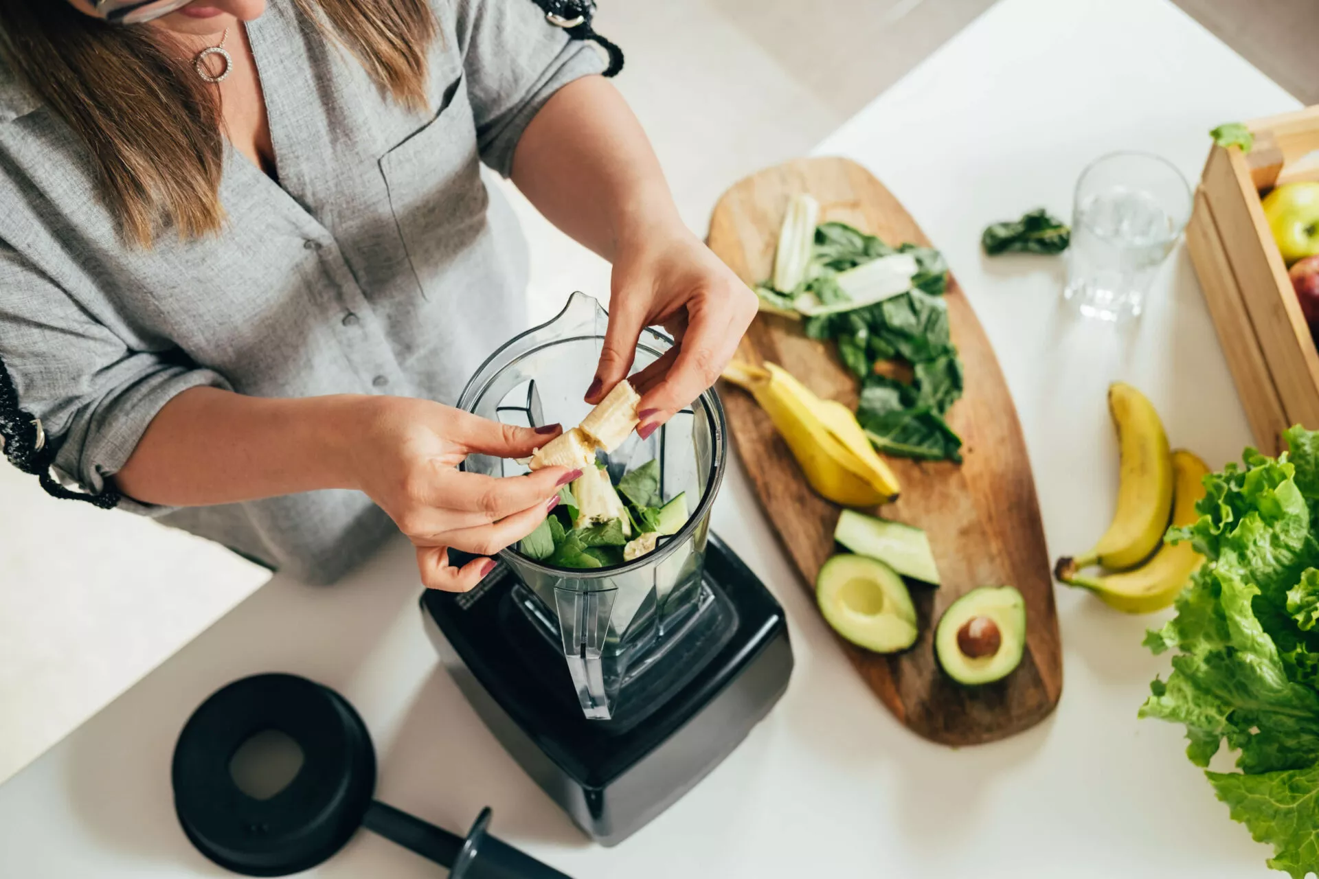 A woman preparing a healthy detox drink in a blender.